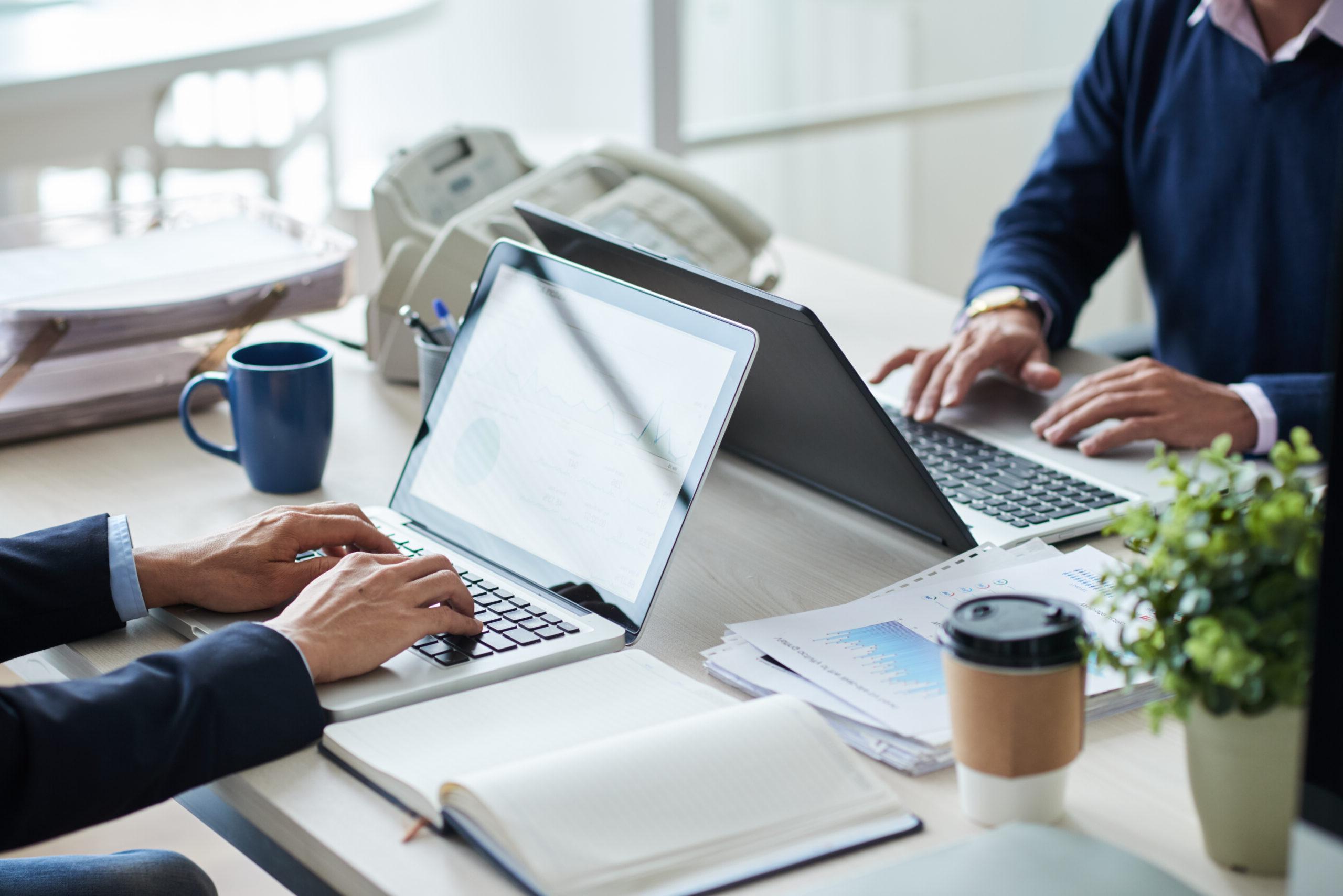 Cropped image of business people working on laptops in office.